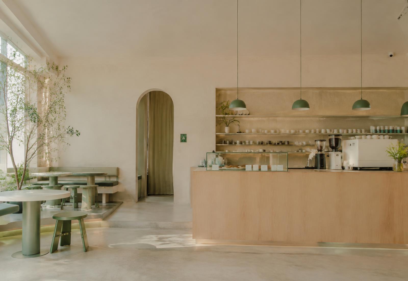 Minimal café interior with cream plaster walls, pale wood counter and plants